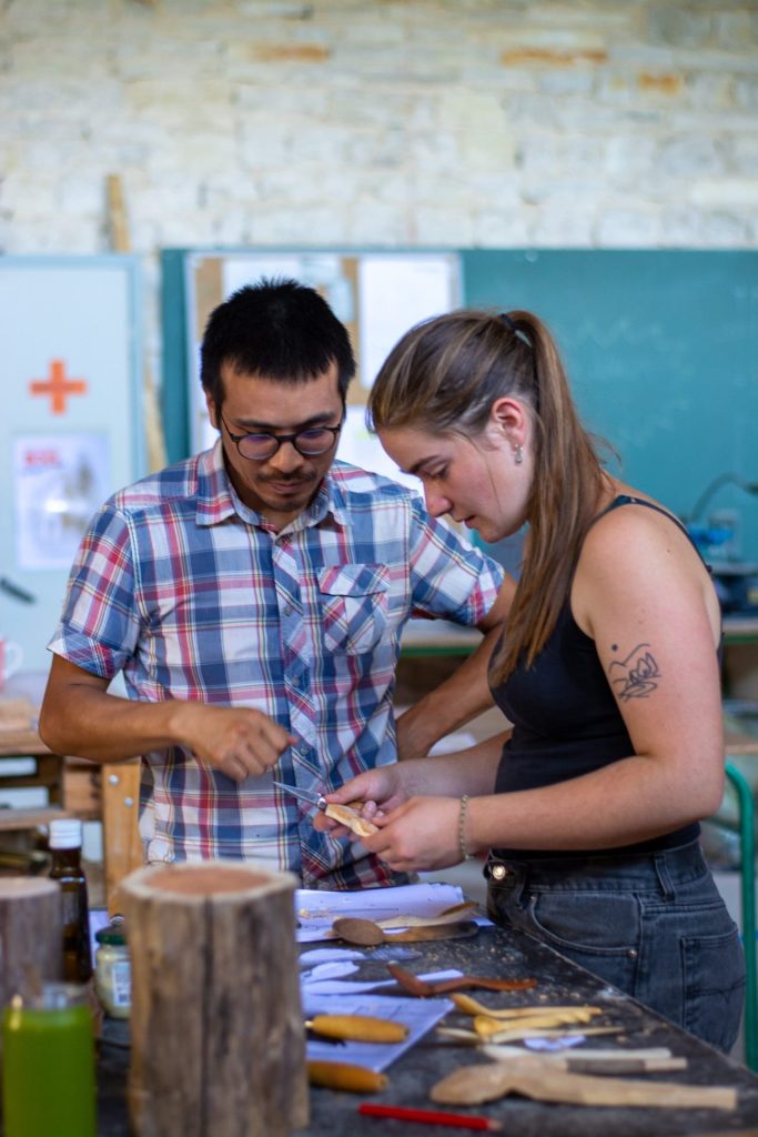 Deux personnes sculptent le bois ensemble.