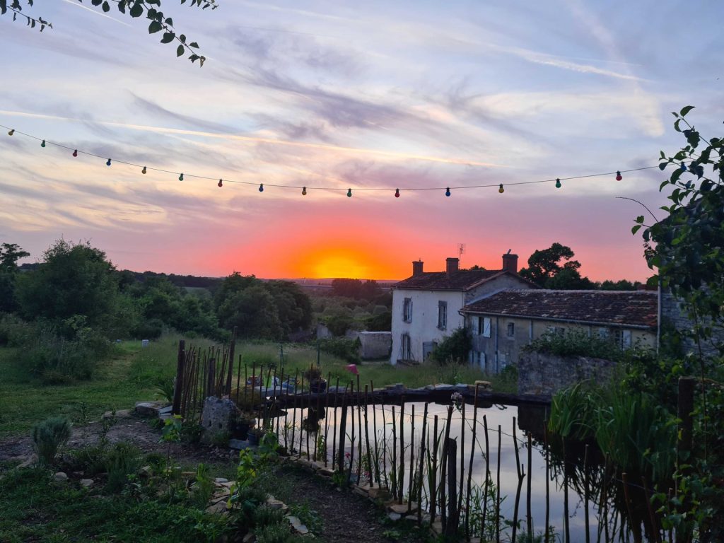 Coucher de soleil sur maison et jardin luxuriant.